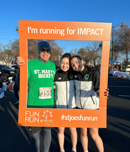 Race participants with frame saying "I'm Running for Impact, Fun Run #stjoesfunrun"